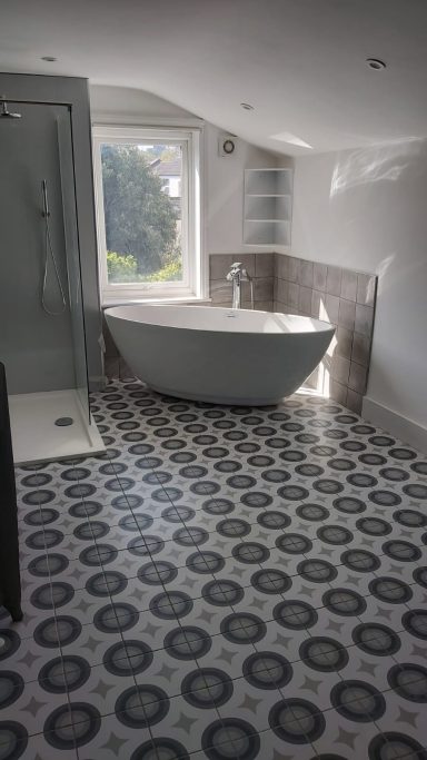 Large bathroom with pattern tiled floor, free standing bath, walk in shower & cast iron radiator