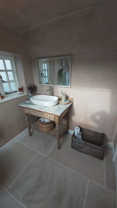 Bathroom with Plastered finished walls, large stone floor tiles. A antique unit with marble top & basin