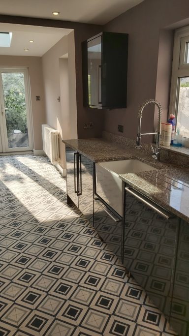 Black kitchen units with marble worktop, butler sink and vinyl flooring