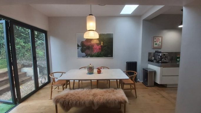 Dining area with grey walls, bi-fold doors and a large picture on the wall
