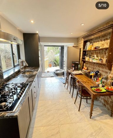 Kitchen with exposed brickwork on one wall, with marble flooring, bi-fold doors